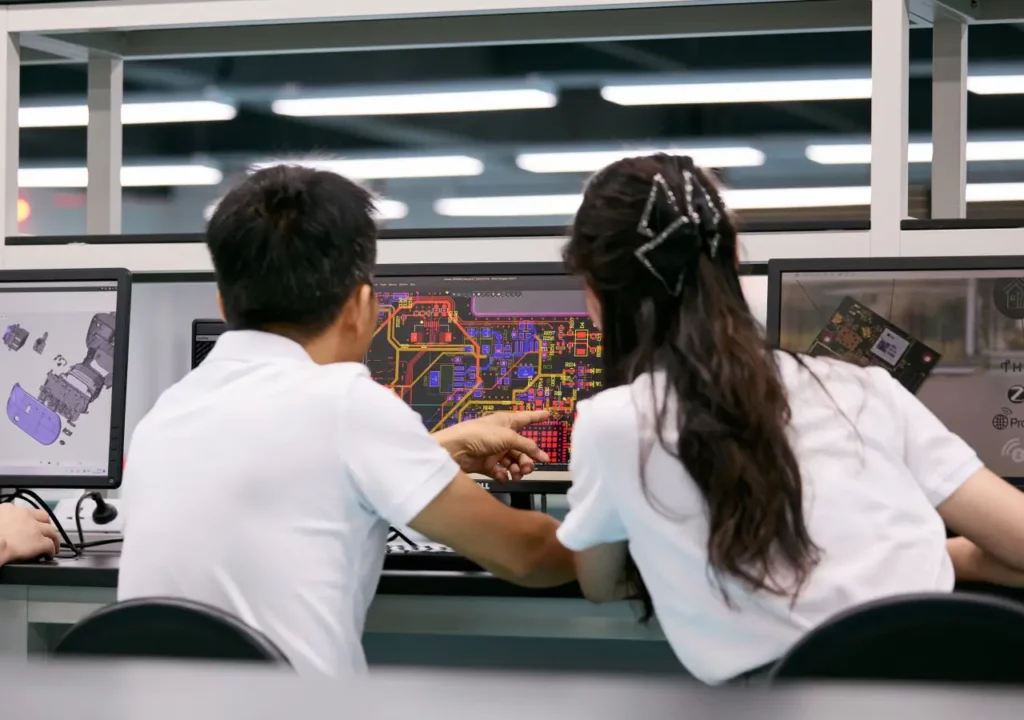 Two Ryder Industries engineers reviewing PCB layout design on monitors in a lab.
